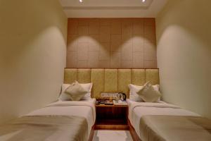 Habitación con 2 camas y mesa con teléfono. en Hotel Amber Suite Near Mumbai Airport, en Bombay