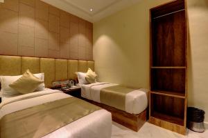 a hotel room with two beds and a shelf at Hotel Amber Suite Near Mumbai Airport in Mumbai