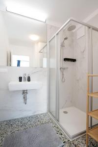 a white bathroom with a shower and a sink at easy flat Villach main plaza in Villach