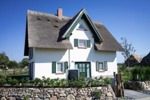 a white house with a thatched roof at Ferienhaus PuddeWohl in Puddemin