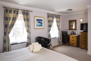 a bedroom with a bed and two windows and a desk at The Coach House Hotel in Pembroke