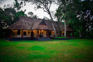 a house with a roof on a green field at Marari Beach Palace in Mararikulam