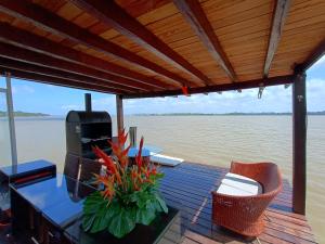 una terraza de madera con mesa y sillas sobre el agua en ILHA DA FANTASIA en Belém