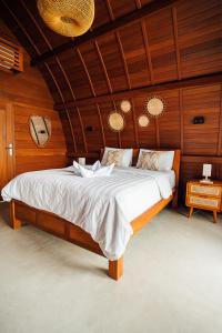 a bedroom with a large bed with wooden walls at HIMA Bungalows in Lagudri