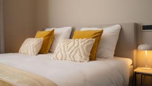 a white bed with yellow pillows on top of it at Hotel Kint in Valkenburg