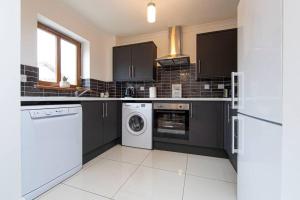 a kitchen with black cabinets and a washer and dryer at Parf’s Place, Troedyrhiw near Bike Park Wales in Troed-y-rhiw