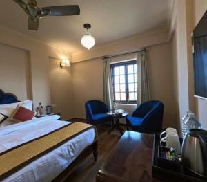 um quarto de hotel com uma cama e duas cadeiras azuis em Hotel Chandra Raj Mahal em Bikaner