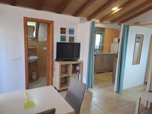 a living room with a tv and a table and a kitchen at Caseta del Riu in Deltebre
