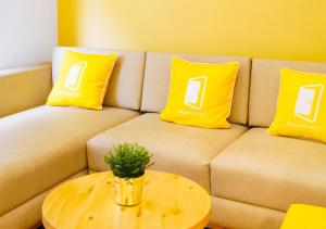 un sofá con 2 almohadas amarillas y una mesa en Bloom Hotel - Heritage Walk en Amritsar