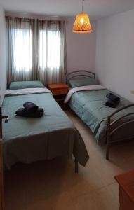 a bedroom with two beds and a lamp and windows at Morello 1A in Calpe