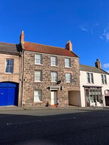 un gran edificio de ladrillo con una puerta azul en una calle en Cara Lodge, Comfortable Self Check-in En-suite Guest Rooms en Berwick-Upon-Tweed