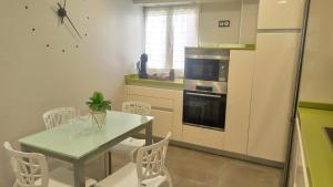 eine Küche mit einem Tisch und Stühlen sowie einem Kühlschrank in der Unterkunft Ohana, Apartamento-CENTRICO-WIFI-ASCENSOR- PARKING PRIVADO GRATIS-SIN CUESTAS in Bermeo