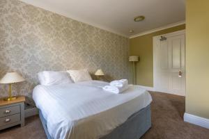 ベッドフォードにあるウッドランド マナー ホテルのベッドルーム(白いシーツを使用した大型ベッド1台付)
