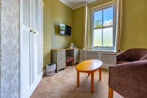 a living room with a couch and a table and a window at Woodland Manor Hotel in Bedford