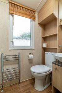 uma casa de banho com um WC e uma janela em Broom Leisure em Annan