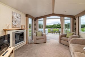 a living room with a fireplace and a tv at Broom Leisure in Annan