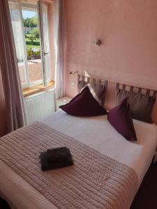 a bedroom with a bed with purple pillows and a window at Relais Vosgien - Hôtel Restaurant "la Table de Sophia" in Saint-Pierremont