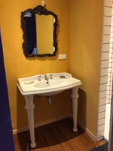 W łazience znajduje się biała umywalka i lustro. w obiekcie La Touratte Bed & Breakfast w mieście Saint-Hubert