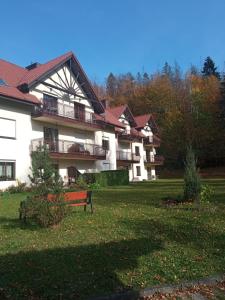 a large building with a bench in the grass at Belweder Apartamenty i Pokoje in Wisła