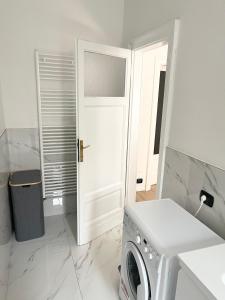 a white laundry room with a washing machine and a door at Ampio bilocale zona Navigli in Milan