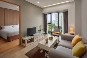 a hotel room with a bed and a living room at Novotel Living Saigon South in Ho Chi Minh City
