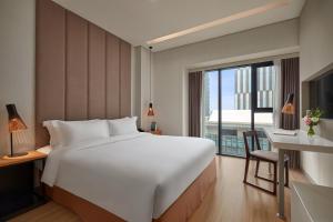 a large white bed in a room with a window at Novotel Living Saigon South in Ho Chi Minh City