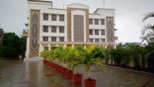 un edificio con una fila de palmeras delante en PUSHPAK HOTEL & CONVENTION en Bhubaneshwar