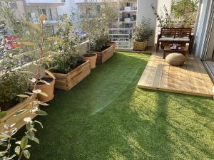 eine Terrasse mit grünem Gras und Topfpflanzen in der Unterkunft Spacious and Sunkissed 3BR & 2 Bathrooms Apartment in Athen