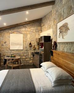 1 dormitorio con cama y pared de piedra en BoisBolchet Ecolodge-SPA en Bouillargues