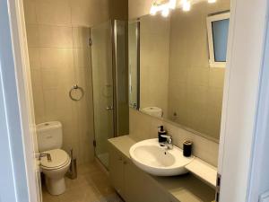 ein Badezimmer mit einem Waschbecken, einem WC und einem Spiegel in der Unterkunft Spacious and Sunkissed 3BR & 2 Bathrooms Apartment in Athen