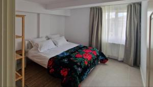 a small bedroom with a bed with a floral blanket at Neo Rustic Bucovina in Gura Humorului