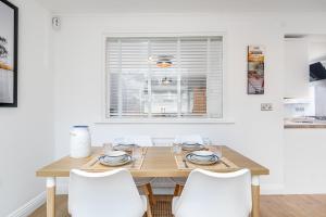 a dining room with a wooden table and white chairs at The High Trees by Night Stay in Birmingham