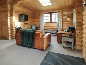 a log cabin room with two couches and a tv at Welcome Hjem Log Cabin in Morpeth