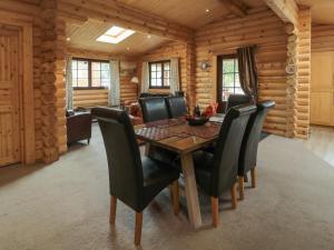 a dining room with a table and black chairs at Welcome Hjem Log Cabin in Morpeth