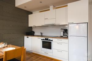 a white kitchen with white cabinets and a table at Holiday in Lapland - Ylläs Gondola apartment, huoneisto 6207 in Ylläsjärvi