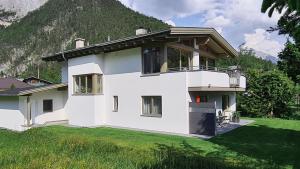 a white house with a mountain in the background at Karwendelgold in Scharnitz