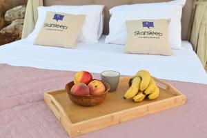 a tray with a bowl of fruit on a bed at Star Sleep Gerani Rethymno in Yeránion