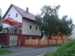 a white and red house with a fence at Apartment Usović in Žabljak