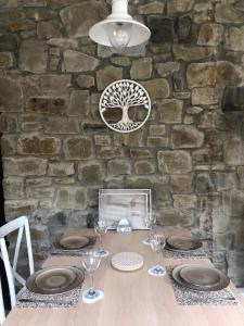 una mesa con platos y gafas y una pared de piedra en Olli's Cottage-Terrace & Jacuzzi en Bristol