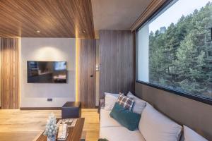 a living room with a white couch and a large window at TODOSIERRANEVADA ZONA BAJA - 2 DORMITORIOS DELUXE REFORMADO - JUNTO A LOS TELECABINAS in Sierra Nevada