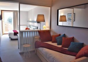 Habitación de hotel con sofá y espejo en Hotel Corrieu, en La Llagonne
