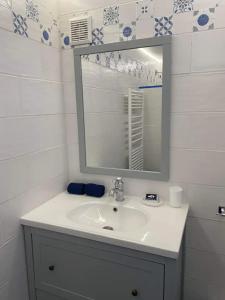 La salle de bains blanche est pourvue d'un lavabo et d'un miroir. dans l'établissement La Noisette, à Équemauville