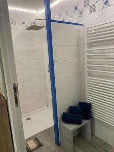 La salle de bains est pourvue d'une baignoire et d'une douche avec des sièges bleus. dans l'établissement La Noisette, à Équemauville