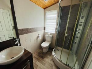 a bathroom with a sink and a toilet and a shower at Crystal Lodge with Hot Tub in Malton