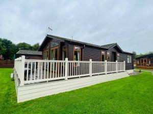 a wooden house with a white fence in a yard at Crystal Lodge with Hot Tub in Malton