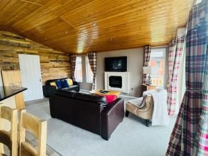 a living room with a leather couch and a tv at Crystal Lodge with Hot Tub in Malton