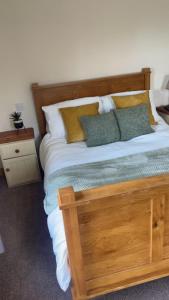 a bedroom with a wooden bed with pillows and a night stand at The Berkeley in Peopleton