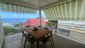 a table and chairs on a balcony with the ocean at Suite Spacieuse 4 étoiles 77m2 vue mer Les Saintes in Trois-Rivières