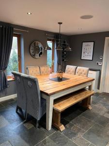a wooden table with chairs and a dining room at 10 sleeper beautiful house with 8 seat hot tub! in Durley