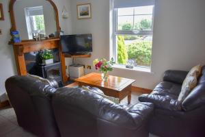 een woonkamer met 2 leren banken en een tafel bij Simply Donegal Adrihidbeg Cottage in Dungloe